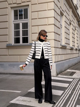 a lady wears a knitted striped cardigan with black pants